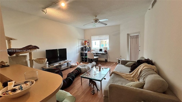 living room with a textured ceiling, ceiling fan, light hardwood / wood-style floors, and track lighting