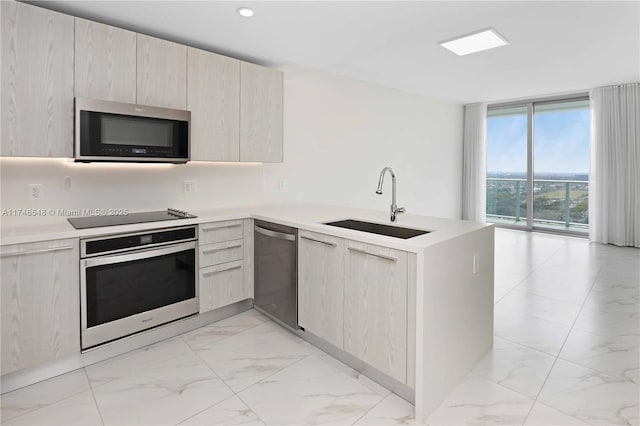 kitchen featuring a wall of windows, kitchen peninsula, stainless steel appliances, and sink