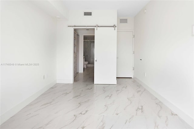 unfurnished bedroom featuring a walk in closet and a barn door