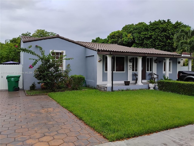 mediterranean / spanish-style home featuring a porch, a front yard, a tile roof, and stucco siding