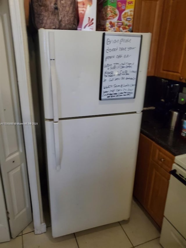 kitchen featuring stove, white fridge, and light tile patterned flooring