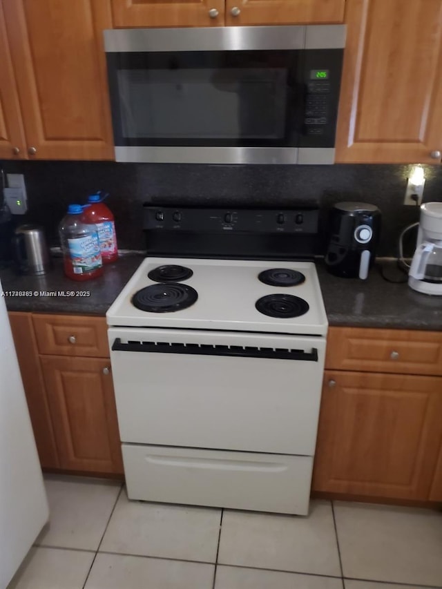 kitchen featuring electric range, light tile patterned floors, and backsplash