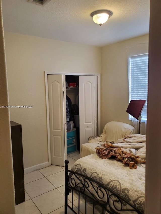 bedroom with light tile patterned floors, a closet, and a textured ceiling