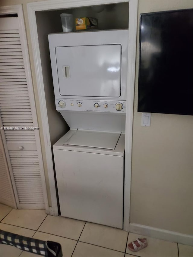 clothes washing area with stacked washing maching and dryer and light tile patterned floors