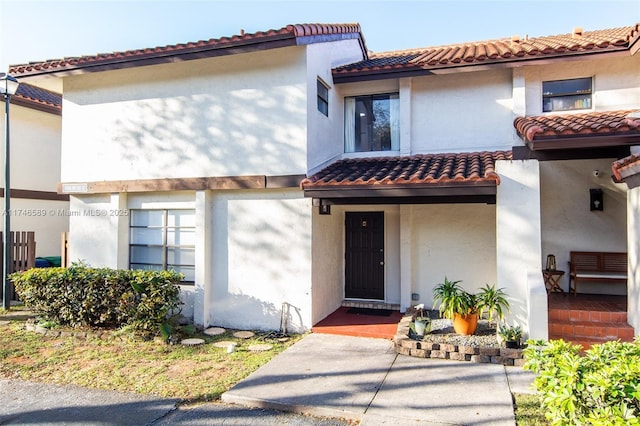 view of front facade with a tiled roof and stucco siding