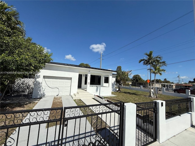 view of front of home with a garage, concrete driveway, a fenced front yard, and stucco siding