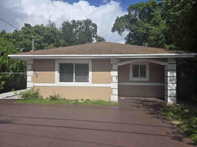 view of front of home featuring roof with shingles and stucco siding