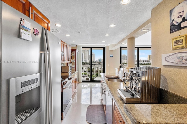 kitchen with sink, stainless steel appliances, light stone countertops, and a wealth of natural light