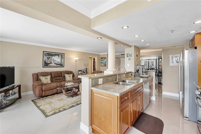 kitchen with appliances with stainless steel finishes, a center island with sink, ornamental molding, sink, and ornate columns