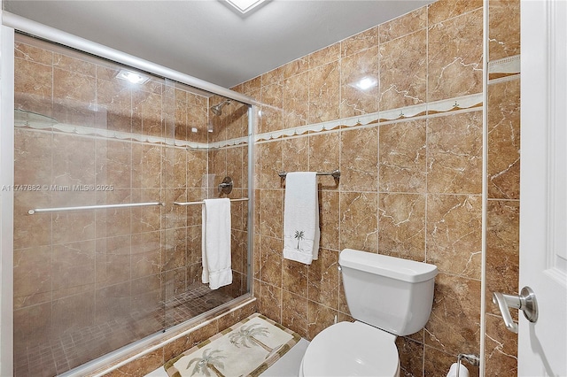 bathroom featuring tile walls, toilet, and a shower with shower door