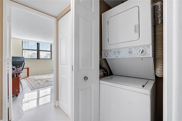 clothes washing area featuring stacked washing maching and dryer and light tile patterned flooring