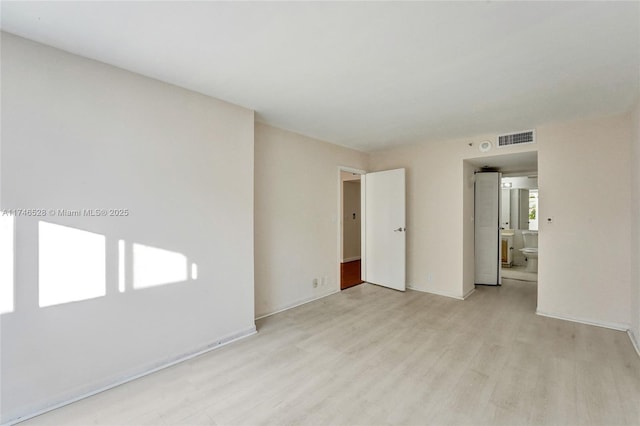 spare room with light wood-style flooring, visible vents, and baseboards