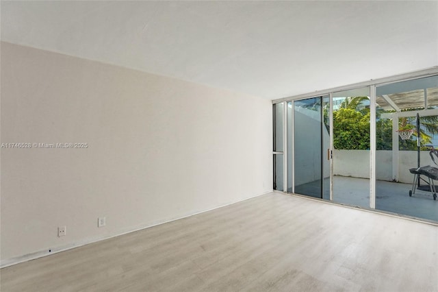 unfurnished room featuring light hardwood / wood-style floors and floor to ceiling windows