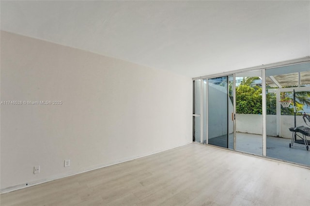 spare room featuring expansive windows and light wood finished floors