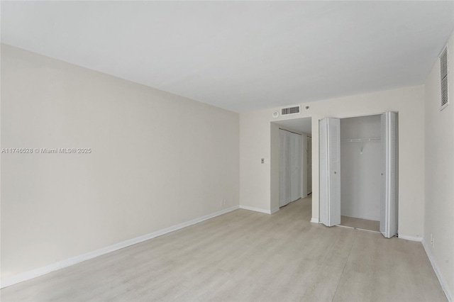 unfurnished bedroom with visible vents, light wood-style flooring, and baseboards