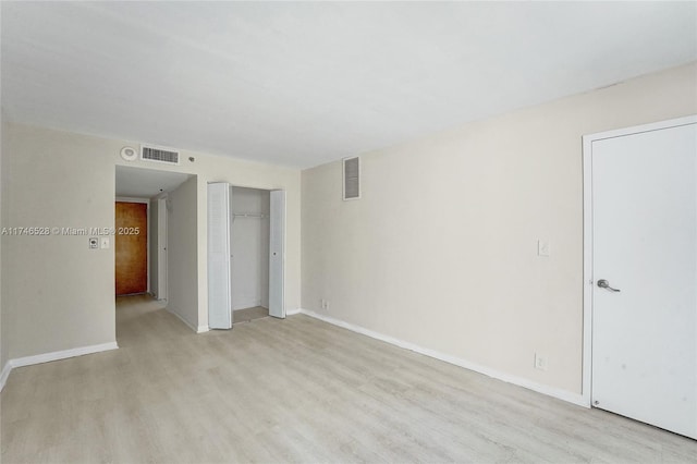 unfurnished room featuring light wood-style flooring, visible vents, and baseboards