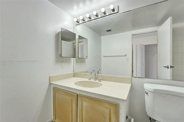 bathroom with toilet, visible vents, and vanity