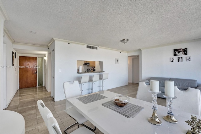 tiled dining space featuring a textured ceiling and crown molding