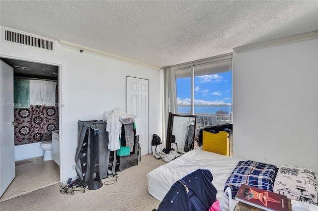 bedroom featuring a water view, carpet floors, floor to ceiling windows, and a textured ceiling