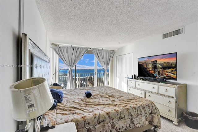 bedroom with a textured ceiling, access to outside, and light colored carpet