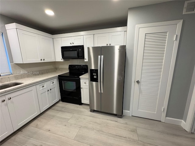 kitchen featuring decorative backsplash, sink, white cabinetry, and black appliances