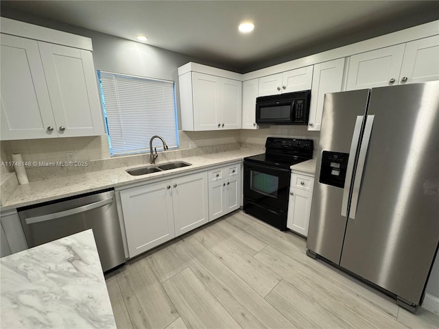 kitchen featuring sink, black appliances, white cabinets, light stone countertops, and decorative backsplash