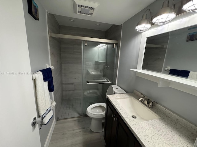 bathroom featuring hardwood / wood-style flooring, vanity, an enclosed shower, and toilet