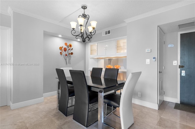 dining space featuring a textured ceiling, ornamental molding, and a notable chandelier