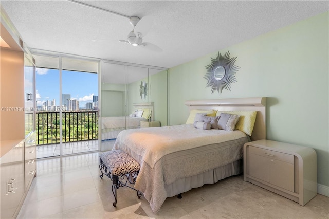 bedroom with ceiling fan, access to outside, a textured ceiling, and a wall of windows