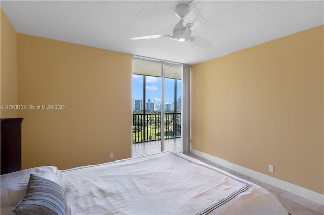 bedroom featuring a textured ceiling, ceiling fan, access to exterior, and floor to ceiling windows