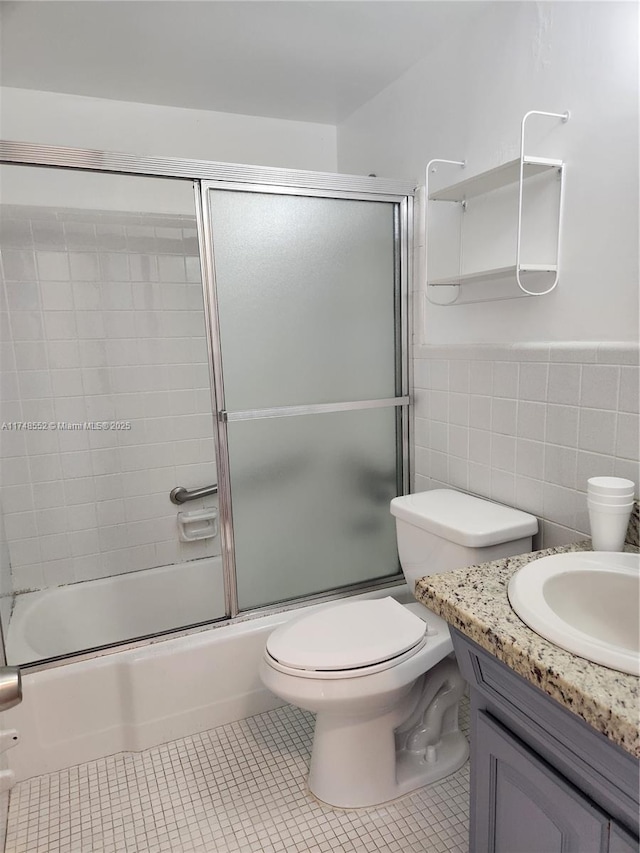455 Golden Isles Dr Unit 309, Hallandale Beach, FL 33009 - full bathroom featuring tile patterned flooring, bath / shower combo with glass door, toilet, tile walls, and vanity