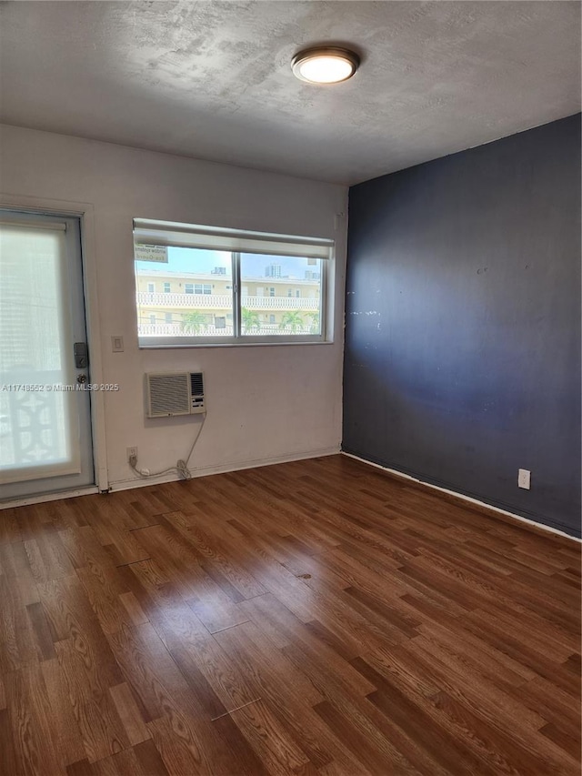 455 Golden Isles Dr Unit 309, Hallandale Beach, FL 33009 - empty room featuring a textured ceiling, a wall mounted air conditioner, and dark hardwood / wood-style floors