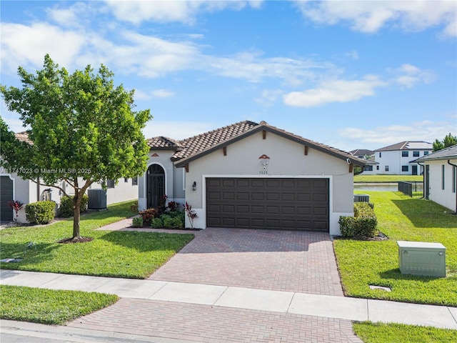 mediterranean / spanish-style home with a garage, a tiled roof, a front lawn, decorative driveway, and stucco siding