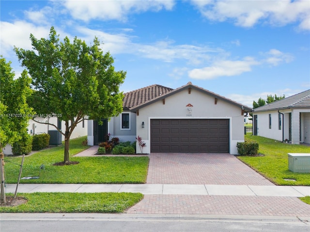 view of front of property featuring stucco siding, a front lawn, a garage, a tiled roof, and decorative driveway