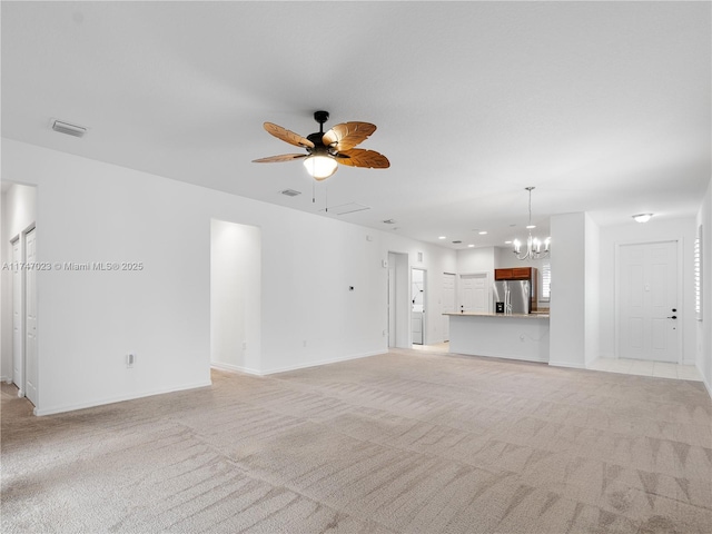 unfurnished living room with ceiling fan with notable chandelier, visible vents, light carpet, and baseboards