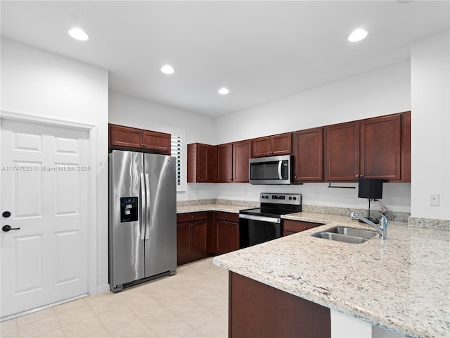 kitchen featuring appliances with stainless steel finishes, light stone countertops, recessed lighting, a sink, and a peninsula