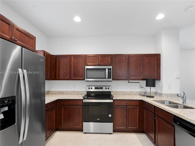 kitchen with a sink, appliances with stainless steel finishes, light stone counters, and recessed lighting