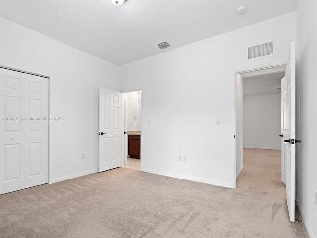 unfurnished bedroom featuring visible vents, a closet, and light carpet