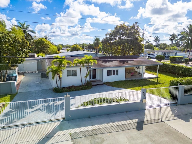 view of front of property with a gate, stucco siding, a front lawn, concrete driveway, and a fenced front yard