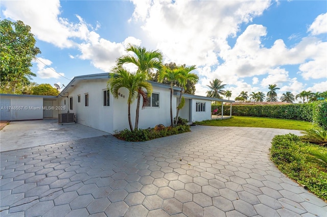 rear view of house with a yard, stucco siding, a patio, and central AC