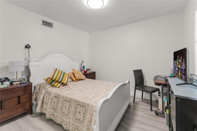 bedroom with light wood-type flooring, visible vents, and baseboards