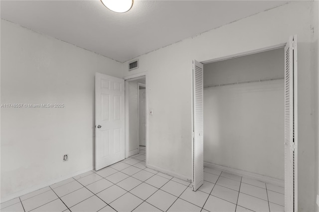 unfurnished bedroom featuring light tile patterned floors, visible vents, and a closet