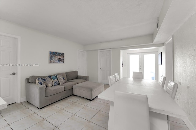 living room with light tile patterned floors, french doors, baseboards, and a textured wall