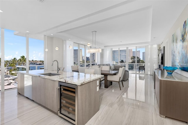 kitchen with wine cooler, an island with sink, a sink, and a city view