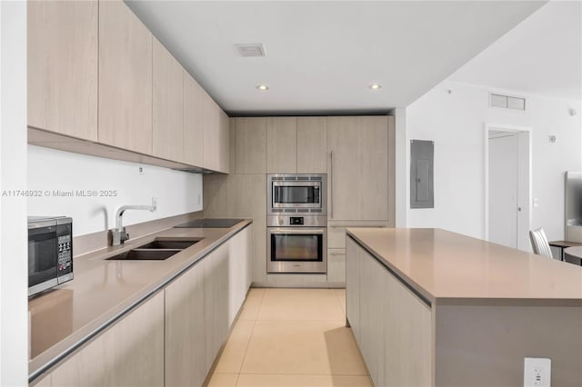 kitchen with electric panel, sink, light tile patterned floors, appliances with stainless steel finishes, and light brown cabinetry