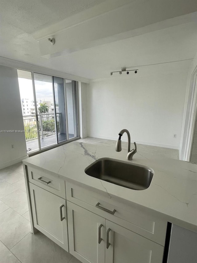 kitchen featuring light tile patterned floors, sink, a textured ceiling, white cabinets, and light stone countertops