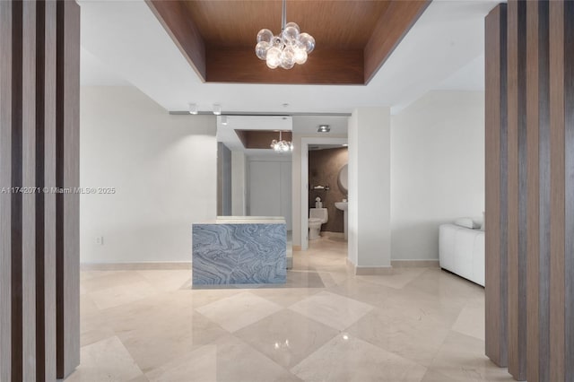 hall featuring wood ceiling, a raised ceiling, baseboards, and an inviting chandelier