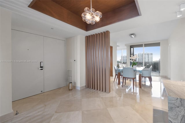 entrance foyer featuring wooden ceiling, a notable chandelier, a city view, floor to ceiling windows, and a raised ceiling