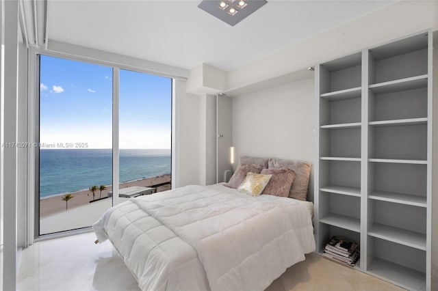 bedroom featuring floor to ceiling windows, a water view, a beach view, and light tile patterned floors