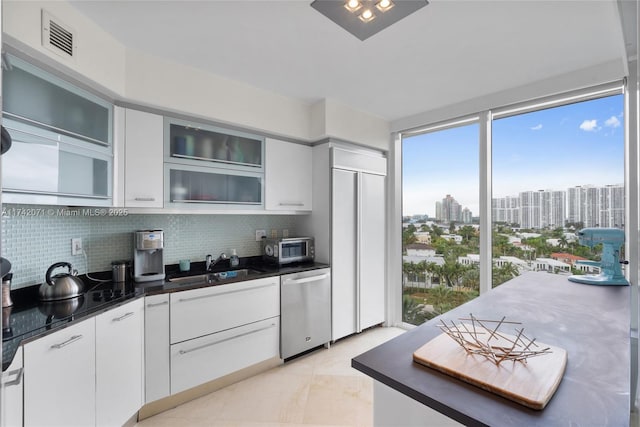 kitchen featuring stainless steel appliances, a view of city, glass insert cabinets, and white cabinets